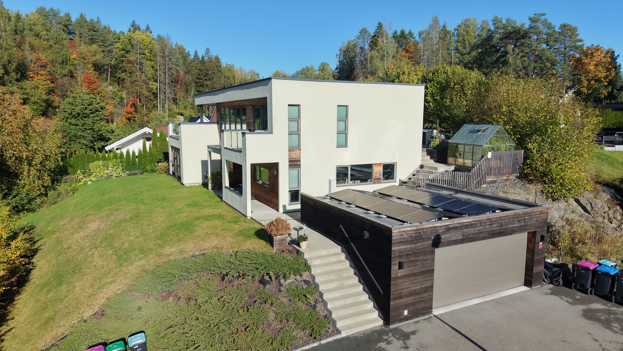 Dronebilde av en moderne hvit bolig med hage
